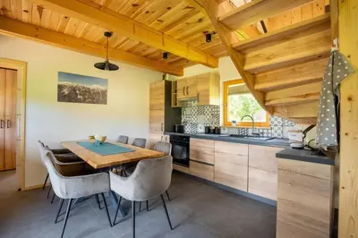a kitchen with a wooden ceiling and a table and chairs at A Nest Under the Karawanks in Žirovnica