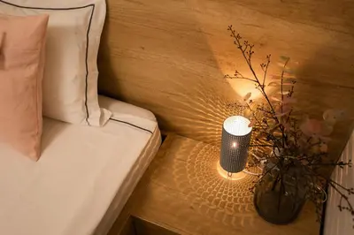 a bed with a lamp on a table with a vase at Apartments Gros in Radeče