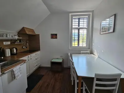 a white kitchen with a table and a window at Hadam's Apartments in Bled