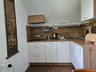 a kitchen with white cabinets and a wooden wall at Hadam's Apartments in Bled
