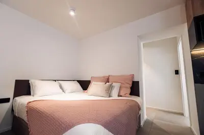 a bedroom with a bed with pink and white pillows at APARTMENTS Goldi Superior in Stahovica