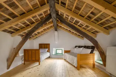 a bedroom with a bed and a desk in a attic at Karst Heritage Retreat in Štanjel