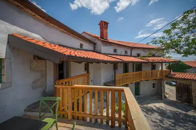 a house with a wooden porch and a deck at Karst Heritage Retreat in Štanjel