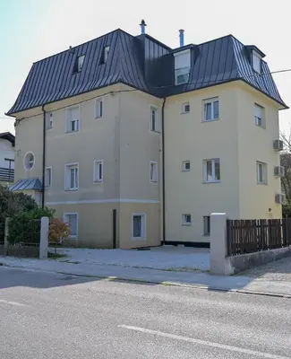 a large white building with a black roof at Blue apartment with FREE parking in Ljubljana