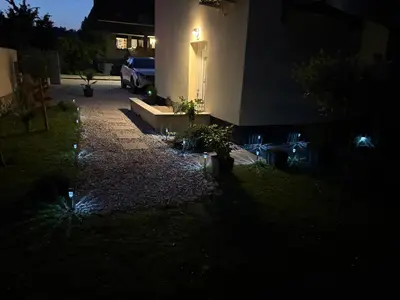 a house lit up at night with a driveway at Blue apartment with FREE parking in Ljubljana