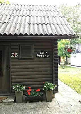 a building with two potted plants and a sign on it at Cosy Retreat Čatež in Čatež ob Savi