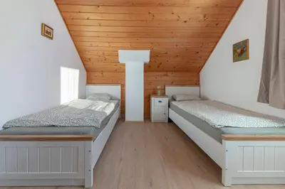 two beds in a attic room with wooden ceilings at Holiday Home Kersnik in Bohinj