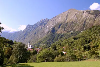 a mountain with a village and a church in a field at Apartments Ivančič in Kobarid
