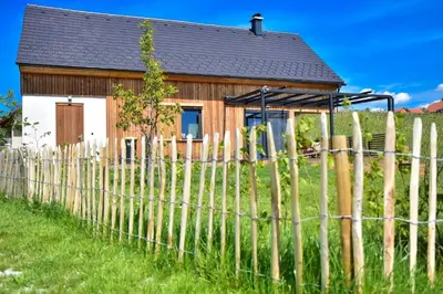 a wooden house with a fence in front of it at Hisa Vukan - Eco House in middle of vineyard with Sauna! in Miklavž pri Ormožu