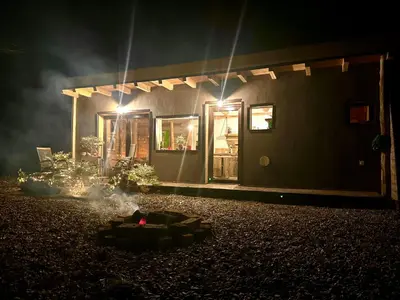 a house lit up at night with a fire in front at Living Forest Resort in Moravske Toplice