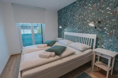 a bedroom with two beds and a wall with floral wallpaper at APARTMA LAMBERGER in Žirovnica