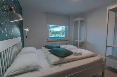 a bedroom with a bed with pillows and a window at APARTMA LAMBERGER in Žirovnica