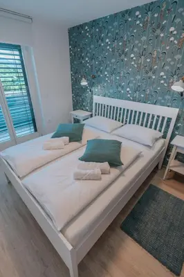 a bedroom with a large white bed with green pillows at APARTMA LAMBERGER in Žirovnica