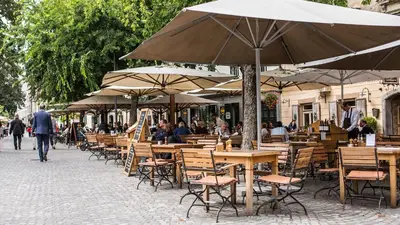 an outdoor cafe with tables and chairs and umbrellas at Valetier apartments in Ljubljana