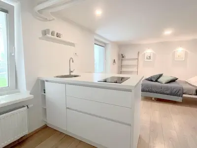 a white kitchen with a sink and a bed at Valetier apartments in Ljubljana