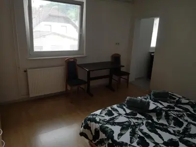 a bedroom with a bed and a table and a window at Sobe Zeleni raj in Podnart