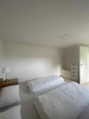 a white bedroom with two beds and a dresser at The Boathouse Apartment in Bled