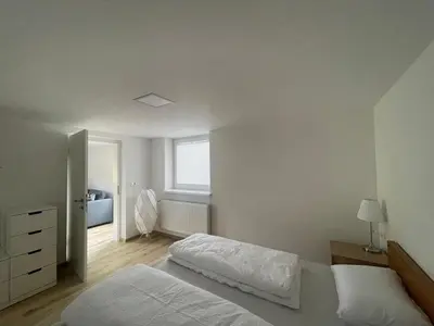a white bedroom with a bed and a window at The Boathouse Apartment in Bled