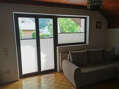 a living room with a couch and two windows at APARTMA MARUŠA in Bled