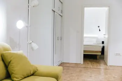 a living room with a yellow couch and a bedroom at Apartment Center II - Kersnikova in Ljubljana