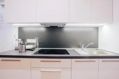 a kitchen with white cabinets and a stove and a sink at Apartment Center II - Kersnikova in Ljubljana