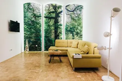 a living room with a yellow couch and a large window at Apartment Center II - Kersnikova in Ljubljana