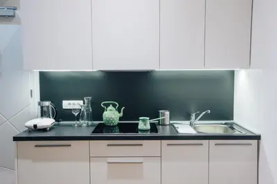 a kitchen with white cabinets and a sink at Apartment Center II - Kersnikova in Ljubljana
