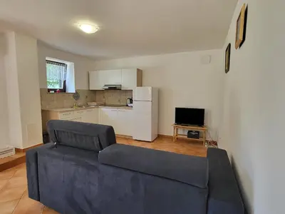 a living room with a couch and a kitchen at Holiday Home Belka with Terrace&BBQ in Tolmin
