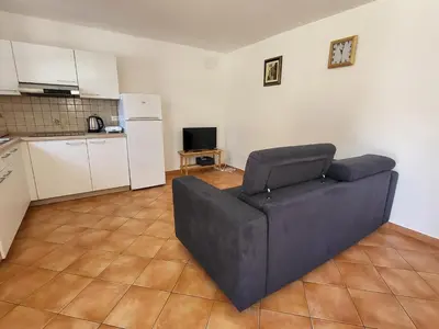 a living room with a couch and a kitchen at Holiday Home Belka with Terrace&BBQ in Tolmin