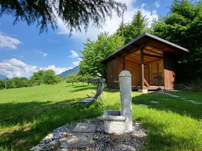 a small cabin in a field with a bench in front of it at Holiday Home Belka with Terrace&BBQ in Tolmin