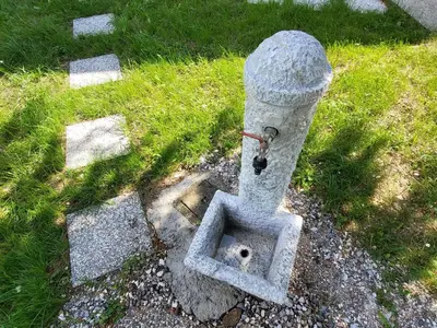 a stone fountain in the middle of the grass at Holiday Home Belka with Terrace&BBQ in Tolmin