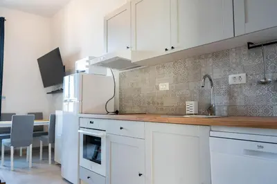 a kitchen with white cabinets and a table with chairs at Apartment TRG in Brežice