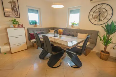 a dining room with a table and chairs and a clock at Vineyard cottage Jelenov hrib in Smarjeske Toplice