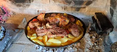 a pan filled with meat and potatoes in an oven at Apartma Relax in Prestranek