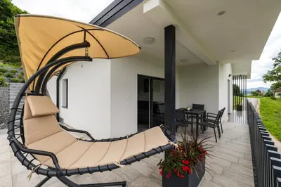 a swinging chair on a patio with a table at Vila Emina in Podčetrtek