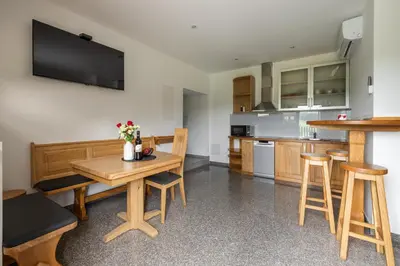 a kitchen with a wooden table with chairs and a counter at Vila Emina in Podčetrtek