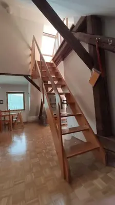 a wooden spiral staircase in a room with a table at MaLu apartment in nature with terrace in Jakovica