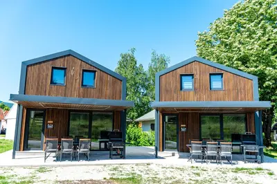a wooden house with tables and chairs in front of it at ARIA DELUXE Mobile Homes with Terme Čatež Tickets in Čatež ob Savi