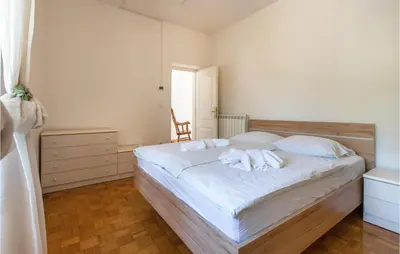 a bedroom with a bed with white sheets and a chair at Amazing Home In Podgorje in Podgorje