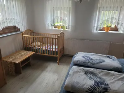 a room with two beds and a crib and windows at Apartma Vida in Videm pri Ptuju