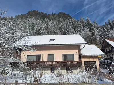 a house covered in snow in front of a mountain at Apartments Mertelj in Kranjska Gora