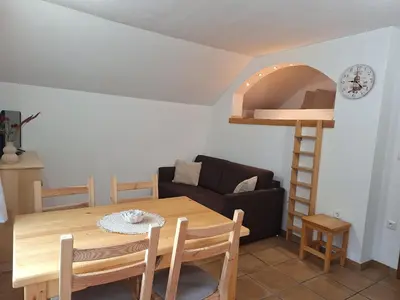 a living room with a dining room table and a chair at Apartments Mertelj in Kranjska Gora