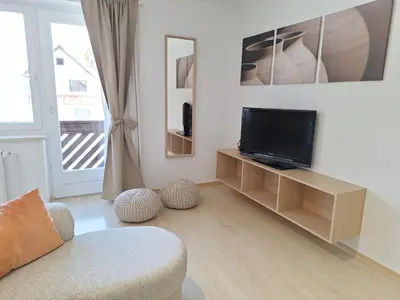 a living room with a tv and a chair at Apartments Mertelj in Kranjska Gora