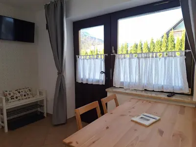 a dining room with a table and a large window at Apartments Mertelj in Kranjska Gora