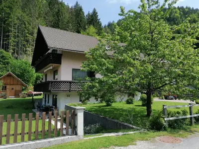 a house with a fence and a tree at Apartments Mertelj in Kranjska Gora