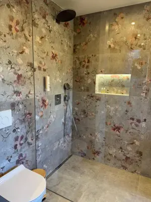 a bathroom with a toilet and a wall with flowers at Vila Urbana Luxury Apartments in Lesce