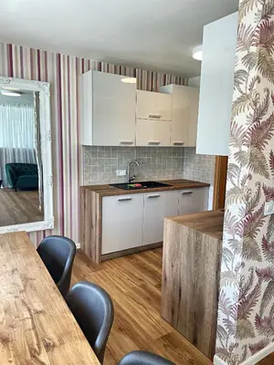 a kitchen with white cabinets and a table and chairs at Vila Urbana Luxury Apartments in Lesce