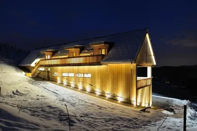 a building with lights on it in the snow at Vino Valdhuber Apartments in Svečina