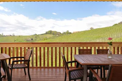 a wooden deck with a table and chairs and a view at Vino Valdhuber Apartments in Svečina