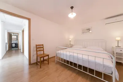a white bedroom with a bed and a chair at Vila Sistiana in Kostanjevica na Krasu